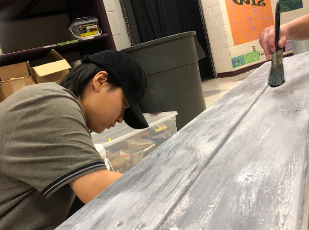 From left to right Design Manager Chris Oh (12) and Wing Head Alison Hoffacker (11) work to paint a bench for the fall show.