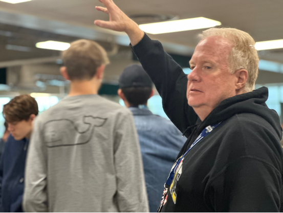 Mr. Christopher Berry directs the students entering the cafeteria to help the flow of traffic.