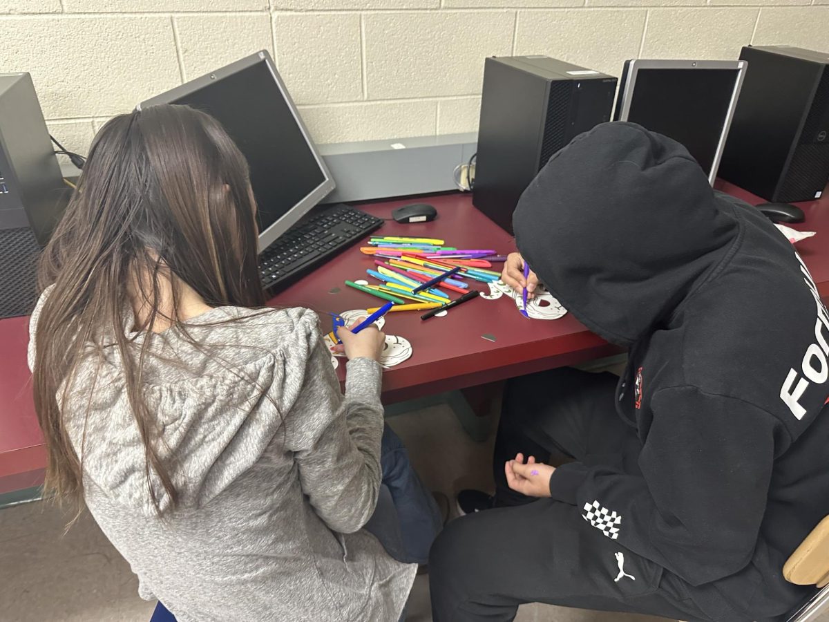 Jorge Ortega and Carly Moore (Class of 2025) coloring their Halloween masks