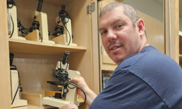 Mr. Bryan Blakely puts away microscopes in the closet of his biology classroom.