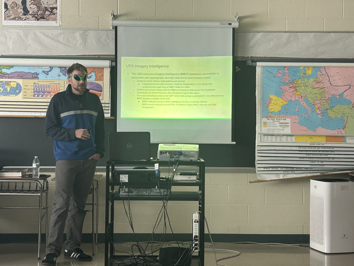 Social Studies teacher Mr. Friedland giving a presentation on UFO hearings to other Social Studies teachers during lunch in Mr. Absher's classroom.