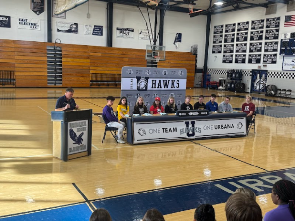 Urbana's top senior student athletes take their seats on signing day!
Sitting from left to right we have Sam Lee, Emily Thornett, Evie Raithel, Paije Brown, Cora Betten, Johnny Crane, TJ Harne, Aidan Himes, JP McEvoy, Brandon Sybrant. The man at the podium is Mitch Rubin. 