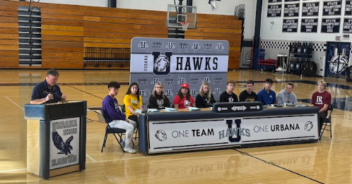 Urbana's top senior student athletes take their seats on signing day!
Sitting from left to right we have Sam Lee, Emily Thornett, Evie Raithel, Paije Brown, Cora Betten, Johnny Crane, TJ Harne, Aidan Himes, JP McEvoy, Brandon Sybrant. The man at the podium is Mitch Rubin. 