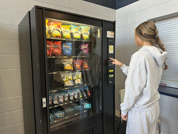 Kyra Satterwhite (Class of 2025) buying a tasty snack from the machine near the auditorium. 