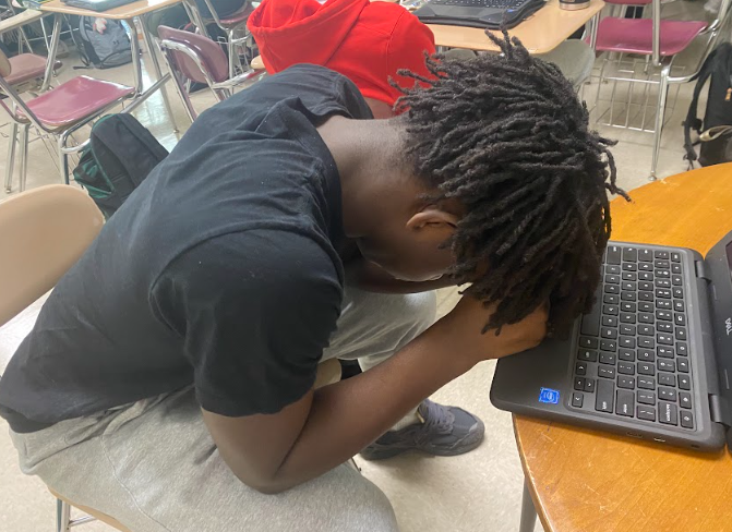 Deron Odame rests his head on the table after submitting his last assignment for the semester.